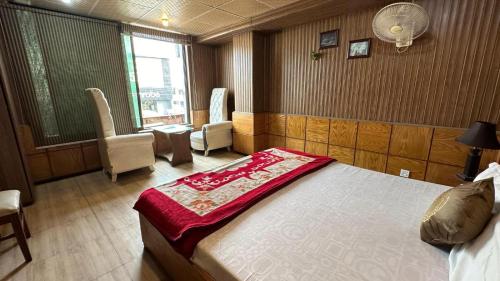 a bedroom with a bed and chairs and a window at Baoo Jee Hotel Islamabad in Rawalpindi