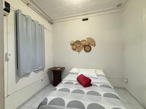 a small room with a bed with a red pillow at Casa Ariano in Recife