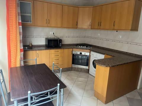 a kitchen with a table and a stove and a microwave at 5 minutes from the beach in Mindelo