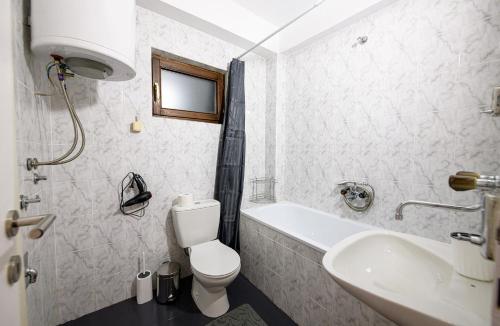 a white bathroom with a toilet and a sink at Sunset in Kriva Palanka