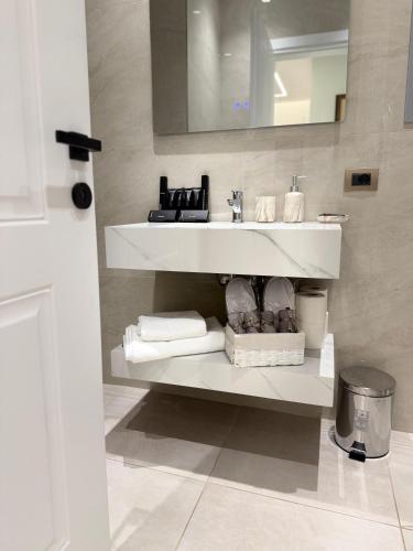 a white bathroom with a sink and towels at Chic Apartament Free Parking in Vlorë