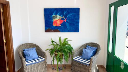 two chairs with blue pillows and a painting at Terraza del Mar in Arrieta