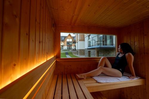 a woman sitting in a sauna looking out the window at Cyrhla Apartamenty - sauna, playroom, free parking & wifi in Zakopane