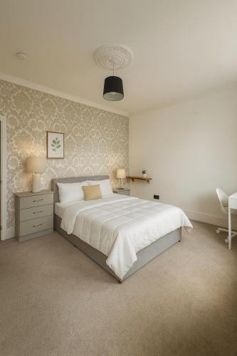 a white bedroom with a large bed and a chair at Wood Green Central Cozy Rooms in London