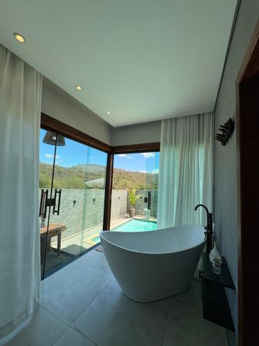 a bath tub in a bathroom with a view of a pool at Cipó Lofts - Serra do Cipó in Santana do Riacho