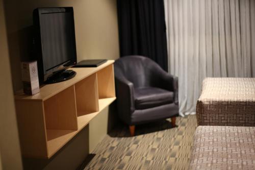 a hotel room with a chair and a tv and a desk at Windsor Castle Hotel in East Maitland