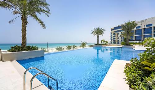 a swimming pool with the ocean in the background at Desert Key - Beachfront Apartments on Saadiyat Island in Abu Dhabi