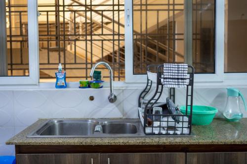 a kitchen sink with a dish drying rack next to it at Ocean Cliff Homes 4 bedroom shared apartment in Mombasa