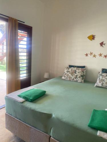 a bedroom with a large bed with green sheets at Casa do Capitao in Guajiru