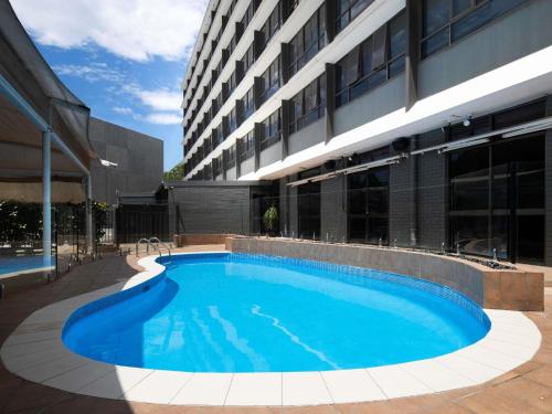 a large swimming pool in front of a building at Mercure Newcastle in Newcastle