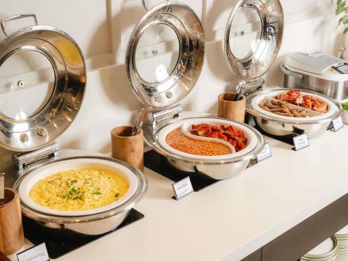un buffet de diferentes tipos de alimentos en sartenes en Mercure Newcastle, en Newcastle