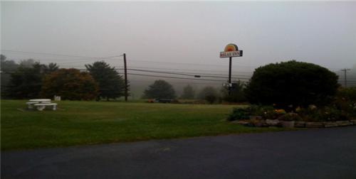 un parque con un cartel y un banco en el césped en Relax Inn Lewisburg, en Lewisburg