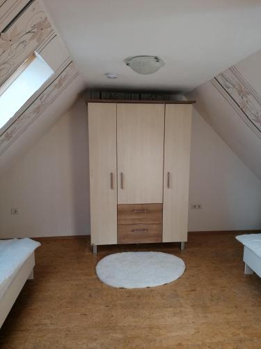 a attic room with a cabinet and a rug at Piratennest in Osteel