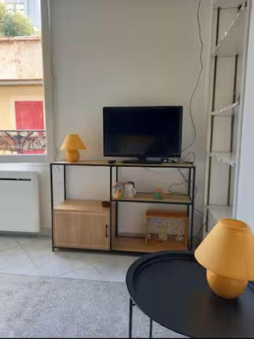 a living room with a tv and a table at Jasmin in Le Vésinet
