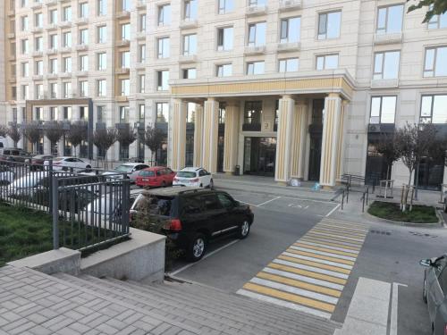a car parked in a parking lot in front of a building at Уютная двух комнатная квартира возле Simketsity mall in Shymkent