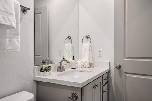a white bathroom with a sink and a mirror at Ultimate Steps to Beach Hot Tub Family Fun in Bolivar Peninsula