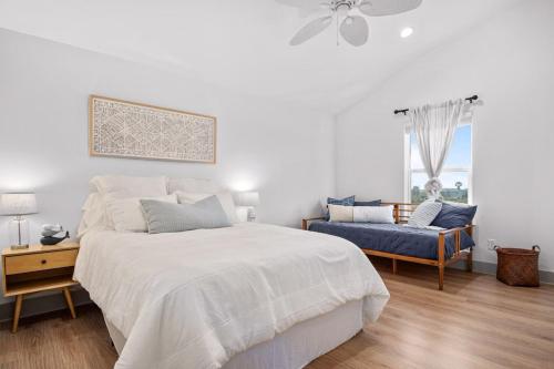 a white bedroom with a large bed and a blue couch at Ultimate Steps to Beach Hot Tub Family Fun in Bolivar Peninsula