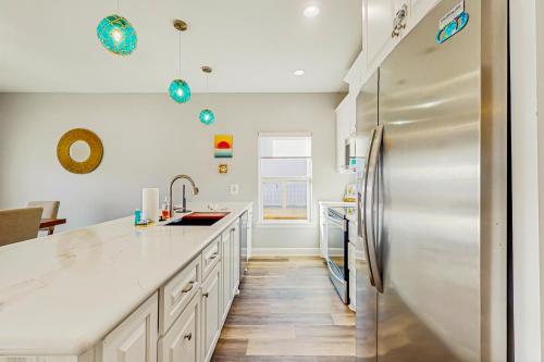 a kitchen with white cabinets and a stainless steel refrigerator at Haven Gulf Views Cargo Lift Large Deck in Crystal Beach