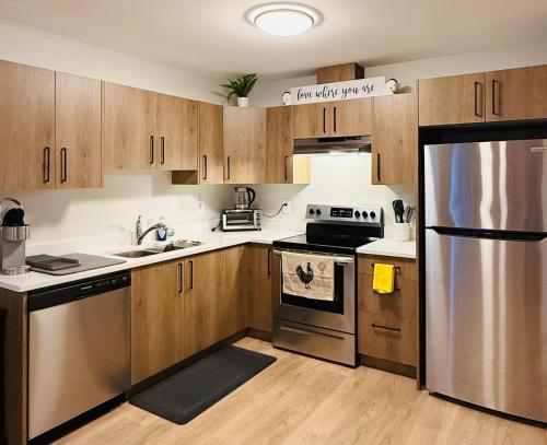 a kitchen with wooden cabinets and a stainless steel refrigerator at Casa Del Mar-A family Suite in Victoria in Langford