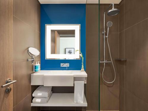 ドバイにあるNovotel Bur Dubai - Healthcare Cityの洗面台とシャワー付きのバスルーム
