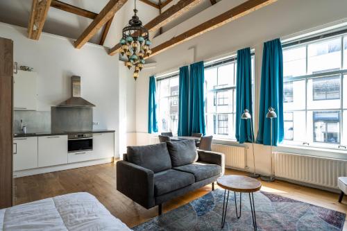 a living room with a chair and a couch and windows at Barbera Guesthouse Hotel Apartments - Experience local life in the Old Centre in Haarlem