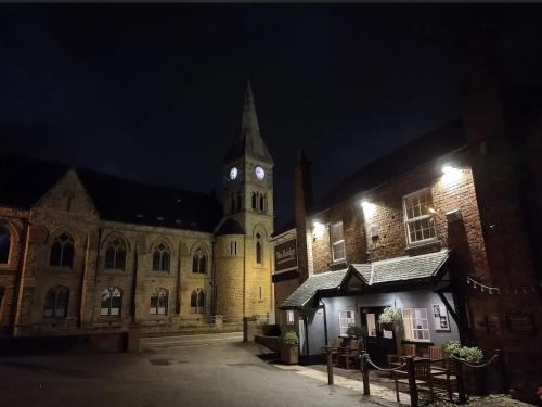 Un gran edificio con una torre de reloj por la noche. en The Bridge inn, en Stone