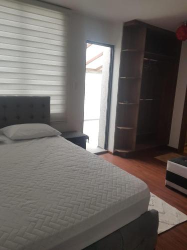 une chambre avec un lit blanc et un placard dans l'établissement Acogedora casa moderna, à Quito