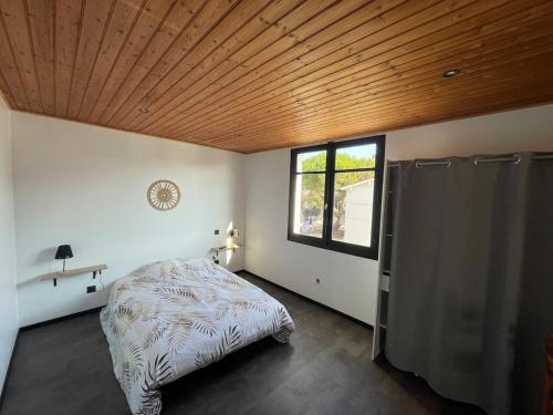 Appartement في لا ترانش سور مير: غرفة نوم بها سرير وسقف خشبي