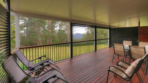 a screened in porch with rocking chairs and windows at Mapleton Falls Accommodation in Mapleton