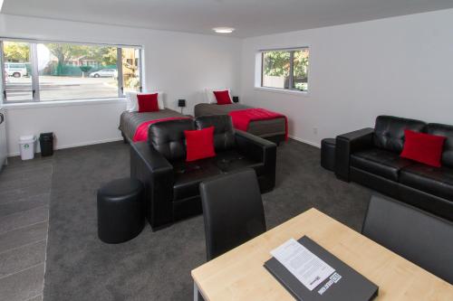 a living room with black leather furniture and red pillows at 538 Great King Motel in Dunedin