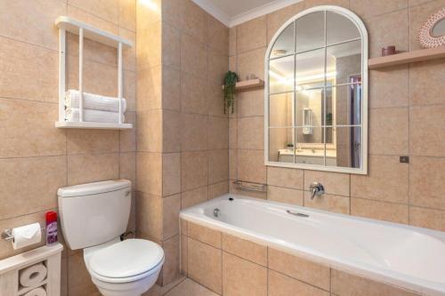 a bathroom with a toilet and a tub and a sink at Emerald Escape With Mountain View & Pool in Cape Town