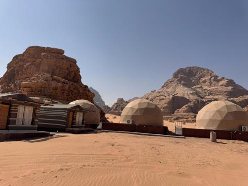 a group of domes in the desert with mountains at Wadi Rum Aviva camp in Wadi Rum