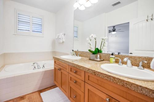 プリンスビルにあるKa Pu'uwai at Nihilani 29Bの洗面台2つ、浴槽1つ、鏡1つを備えたバスルーム