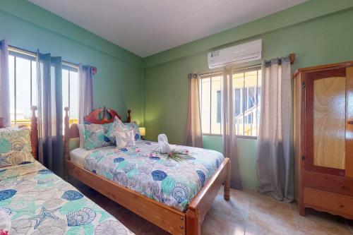サン・ペドロにあるHanna Suite #9 at Laguna Suite -Gold Standard Certifiedの緑の壁のベッドルーム1室、ベッドカバー付きのベッド1台が備わります。