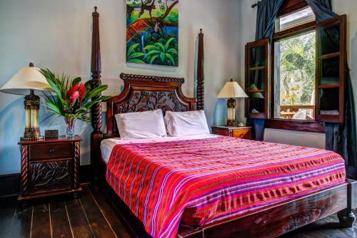 a bedroom with a large bed with a red blanket at Monkey Room at Mahogany Hall -Gold Standard Certified in Bullet Tree Falls