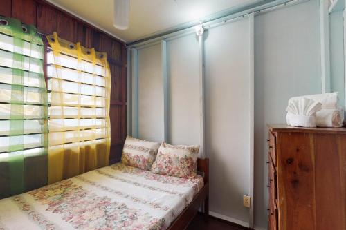 a small bedroom with a bed and a window at Permit at Carol's Cabanas -Gold Standard Certified in Placencia Village