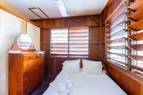 a bedroom with a bed and a dresser and a window at Bonefish at Carol's Cabanas -Gold Standard Certified in Placencia Village