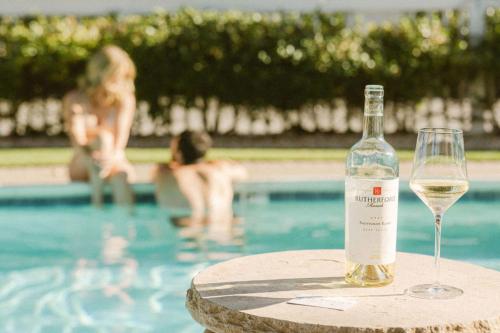 a bottle of wine sitting on a table next to a swimming pool at El Bonita Motel in St. Helena