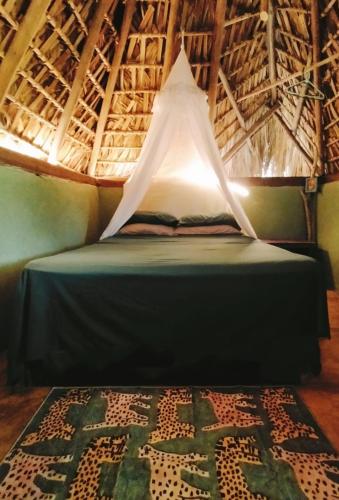 a bed with a canopy in a room with a rug at El Chiringuito, Mermejita in Mazunte