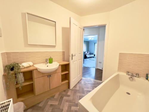 uma casa de banho com uma banheira branca, um lavatório e uma banheira. em Stylish City Apartment with Free Parking near Town em Glasgow