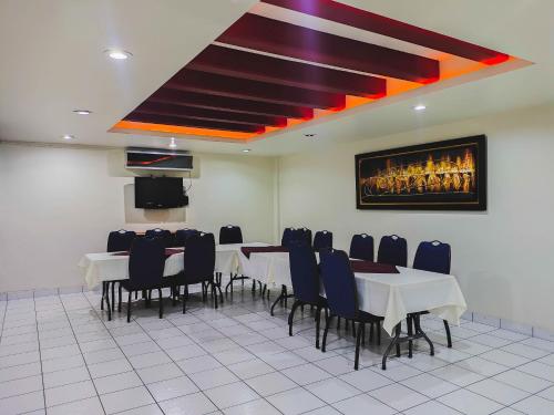 a dining room with tables and chairs and a painting on the wall at Hotel oasis suites in Delicias