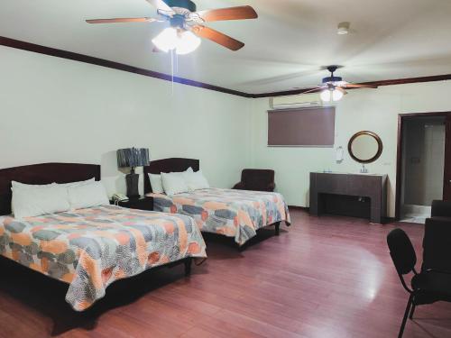 a room with two beds and a ceiling fan at Hotel oasis suites in Delicias
