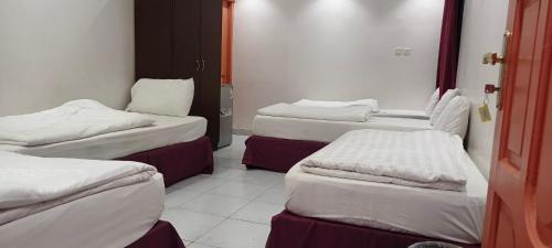a room with three beds in a room at نزل الاوئل in Al Madinah