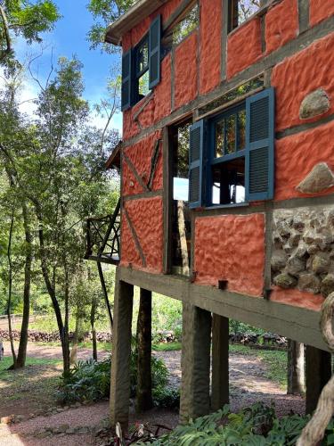 a house constructed out of logs with windows and trees at Casa Ar Fresco in Sapiranga