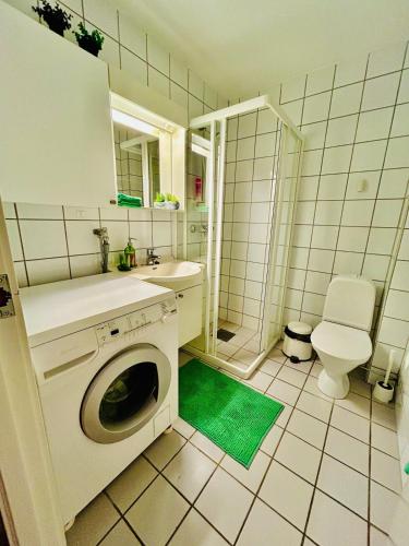 a bathroom with a washing machine and a toilet at Trondheim Fjord Suites Self Checkin And Out in Trondheim