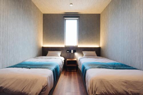two beds in a small room with a window at The Pool House Tokyo Bay in Narashino