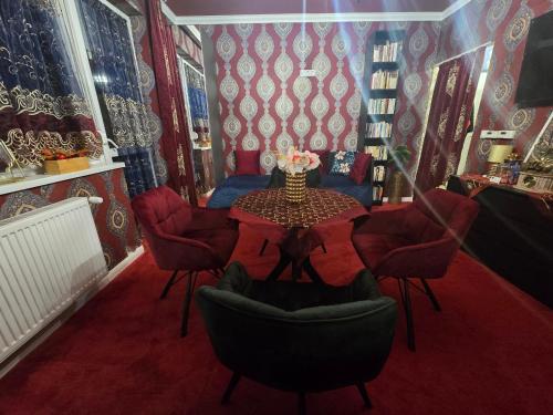 ein Esszimmer mit einem Tisch, Stühlen und roten Wänden in der Unterkunft JEVA Apartman HAJDÚSZOBOSZLÓ in Hajdúszoboszló