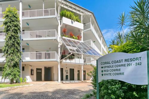 a white apartment building with a sign in front of it at Spindle Cowrie Apartments Palm Cove in Palm Cove