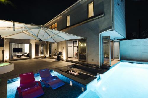 a house with a swimming pool with two blue chairs at The Pool House Tokyo Bay in Narashino