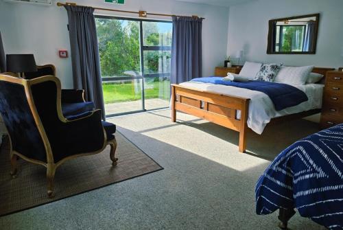 une chambre avec un lit, une chaise et une fenêtre dans l'établissement Hosts on the Coast Tui Hills, à Aongatete